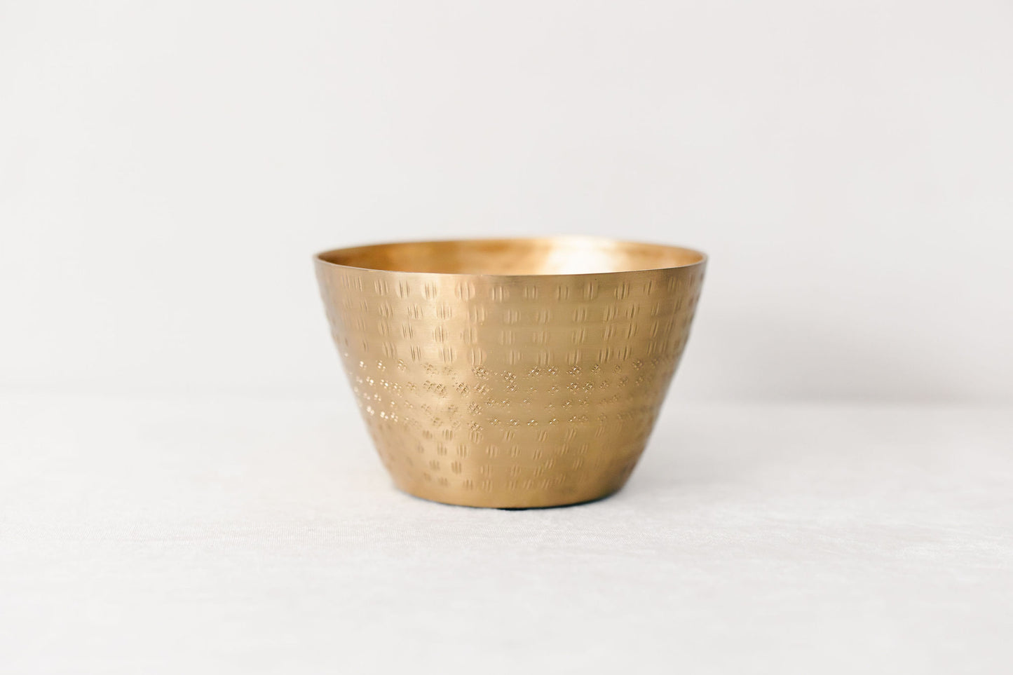 Brass bowl with textured surface on a white background