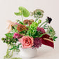Colorful flower arrangement in a white vase on a light background