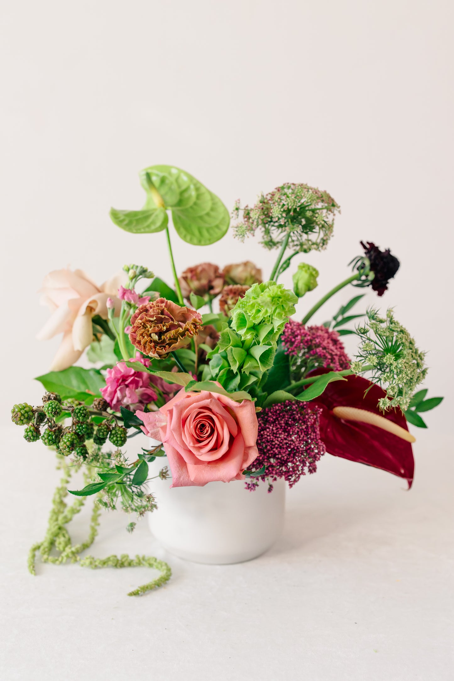 Colorful flower arrangement in a white vase on a light background