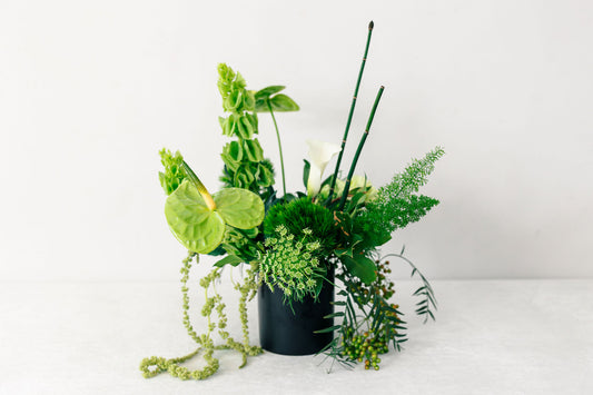 Green floral arrangement on a white surface with a white background