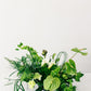 Arrangement of greenery and white flowers on a white background