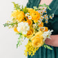 Bouquet of yellow and white flowers held by a person wearing a green dress.