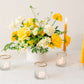 Yellow floral arrangement with yellow candles on a white background