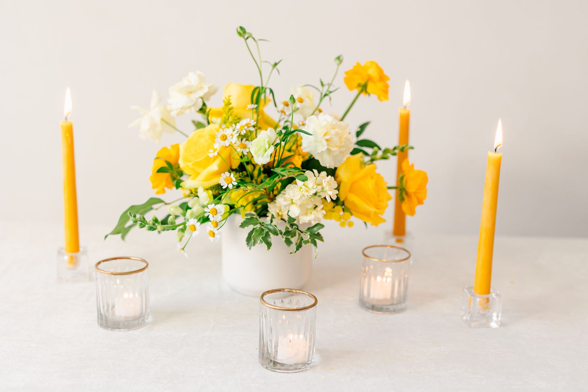 Yellow floral arrangement with yellow candles on a white background