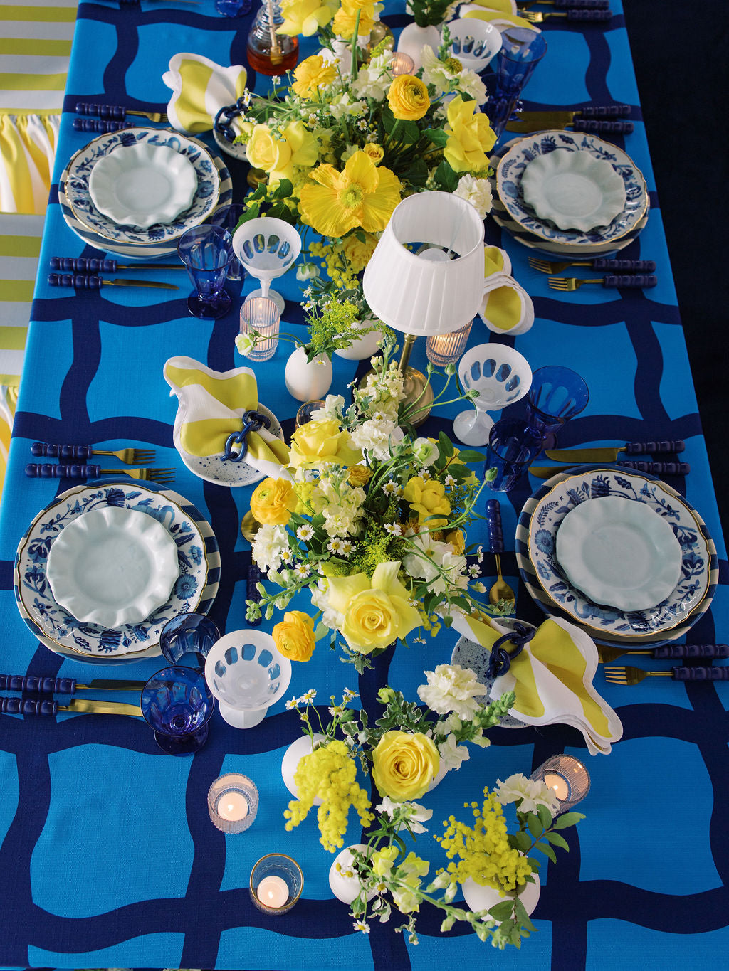 Decorative table setting with floral centerpieces, blue and white tablecloth, and patterned plates.