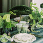 Decorative table setting with green and white elements on a striped tablecloth.