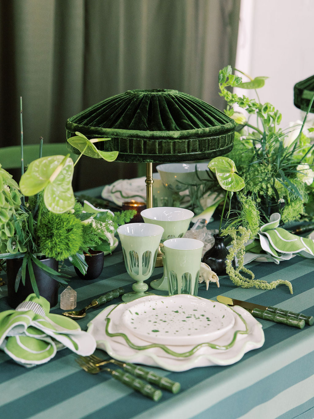 Decorative table setting with green and white elements on a striped tablecloth.