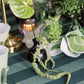 Decorative table setting with greenery, vases, and striped tablecloth.