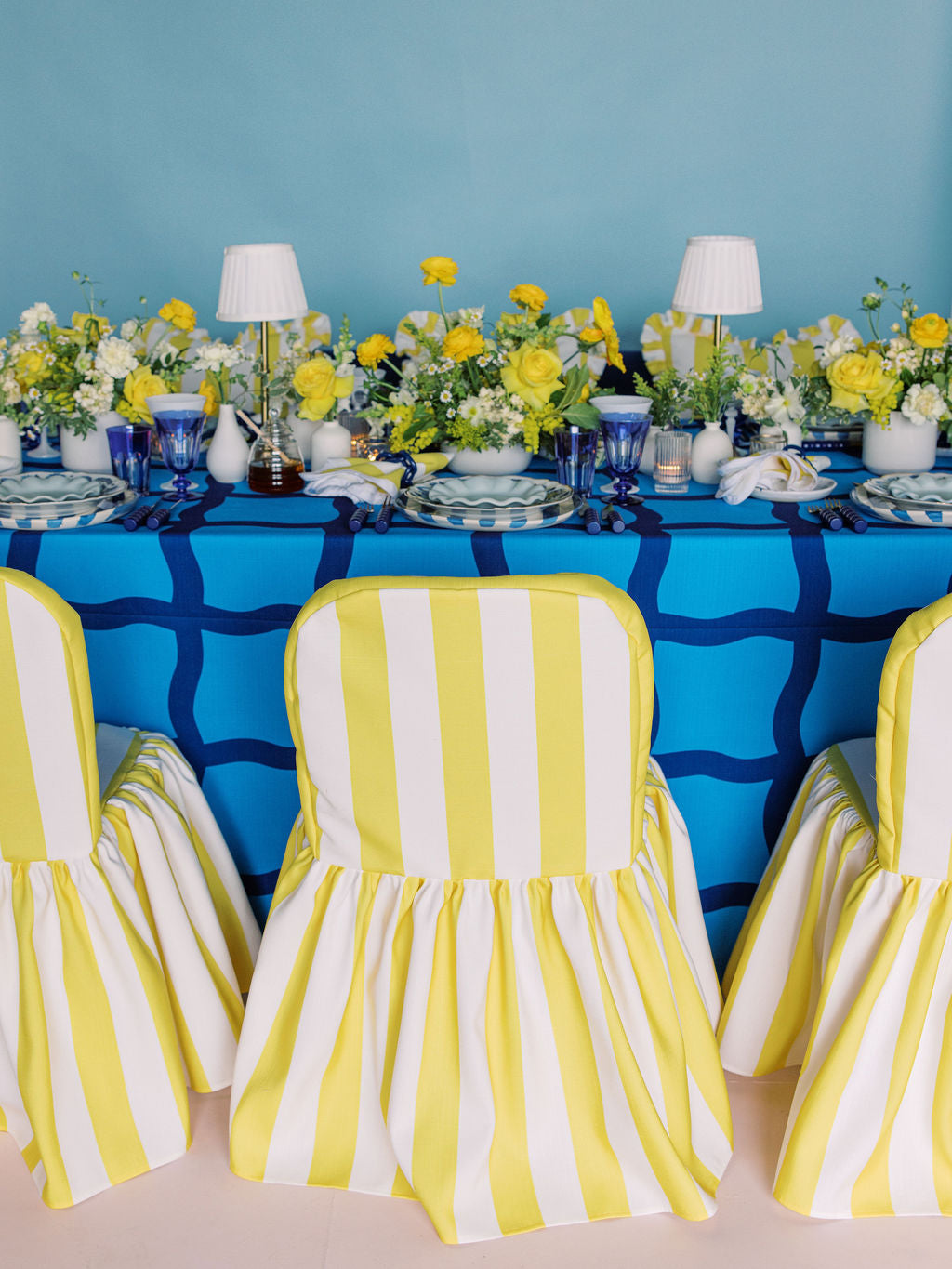 Decorated table with yellow and white striped chairs against a blue wall.