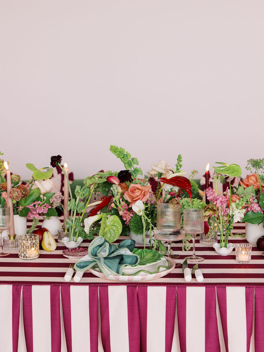Decorative table setting with flowers, candles, and striped tablecloth.