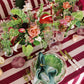Decorative table setting with floral arrangements, candles, and cutlery on a striped tablecloth.