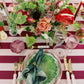 Decorative table setting with floral arrangements, plates, and cutlery on a striped tablecloth.