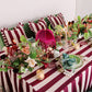 Decorative table setting with striped tablecloth, floral arrangements, and candles.