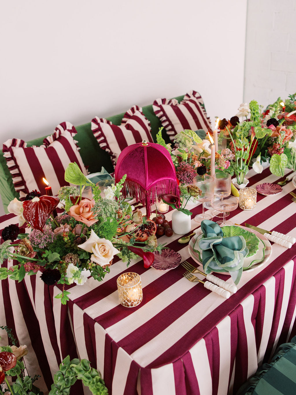 Decorative table setting with striped tablecloth, floral arrangements, and candles.