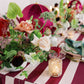Decorative table setting with flowers, candles, and striped tablecloth.