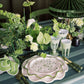 Elegant table setting with green and white decor, including plates, napkins, and a lamp.