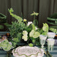 Decorative table setting with greenery and white plates on a dark background