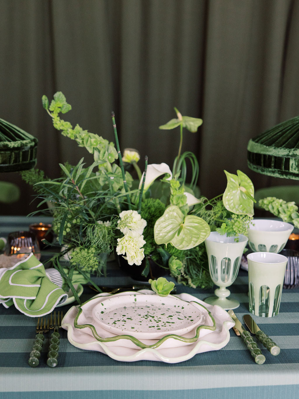 Decorative table setting with greenery and white plates on a dark background