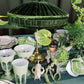 Decorative table setting with green and white elements, including a lamp and plants.