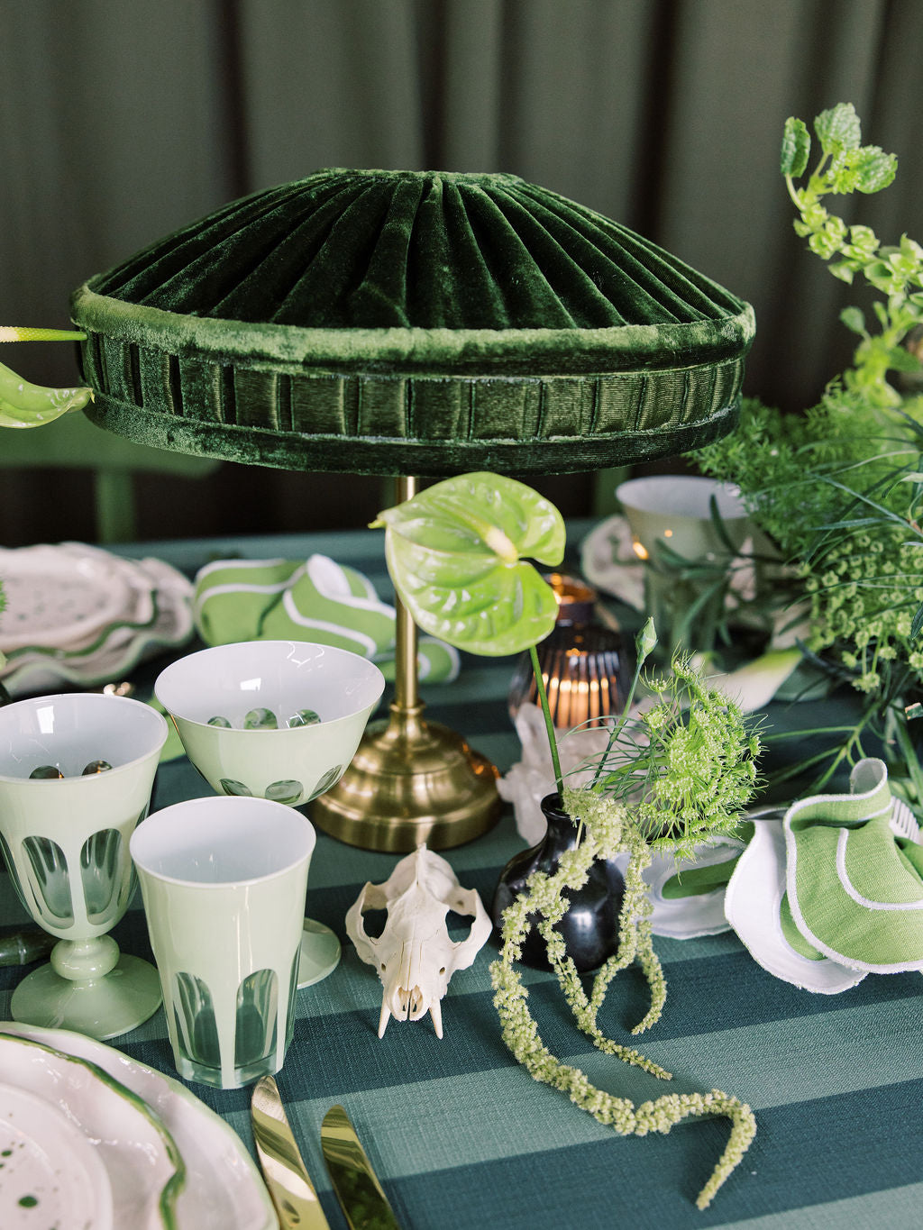 Decorative table setting with green and white elements, including a lamp and plants.