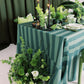 Decorative table setting with green and white striped tablecloth, candles, and floral arrangements.