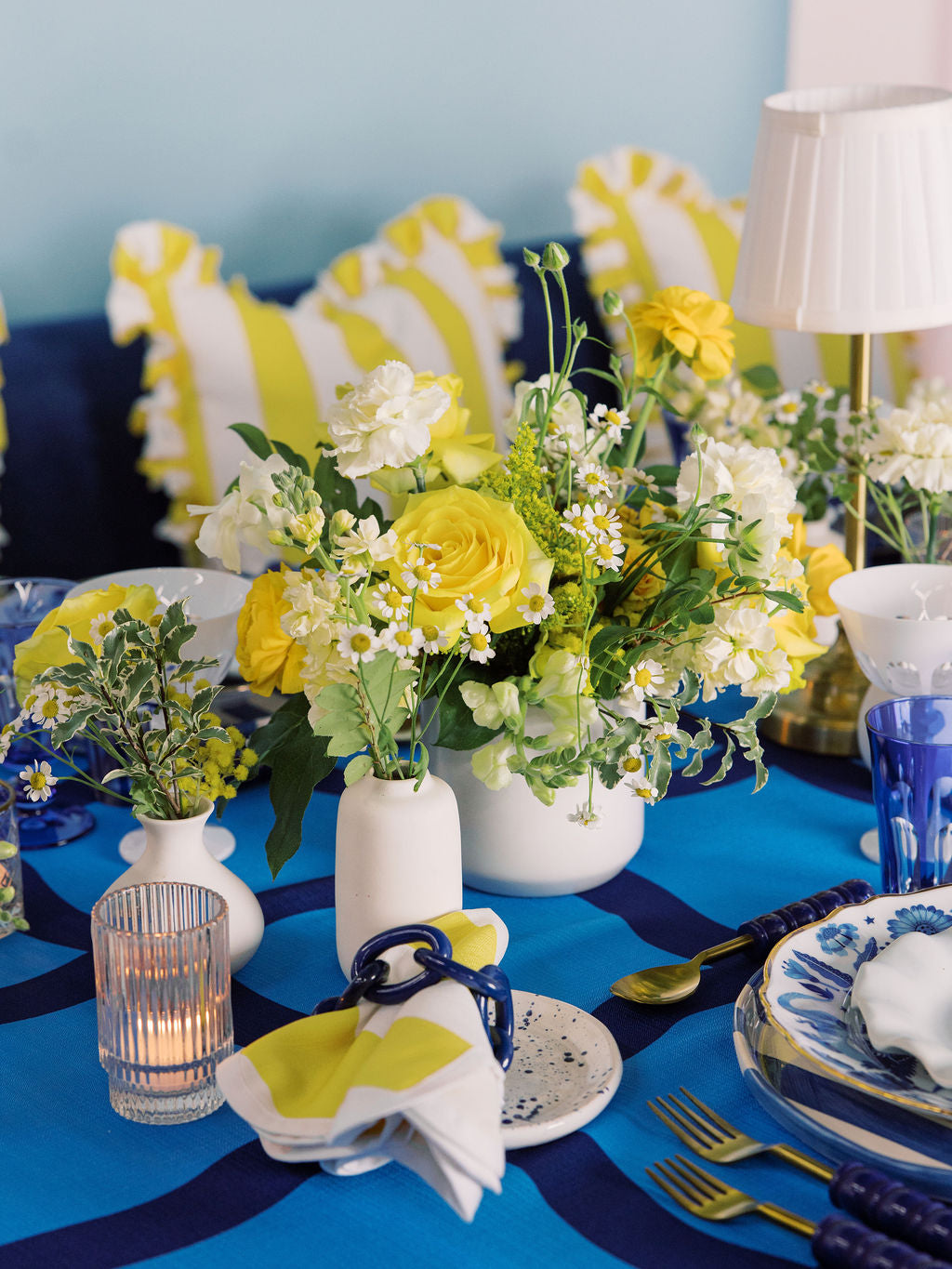 Decorative table setting with yellow and blue elements, including flowers and tableware.