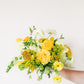Bouquet of yellow and white flowers held by a person on a light background
